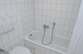 Bad mit Badewanne und Duschvorhang, WC, Spültisch und Spiegel
